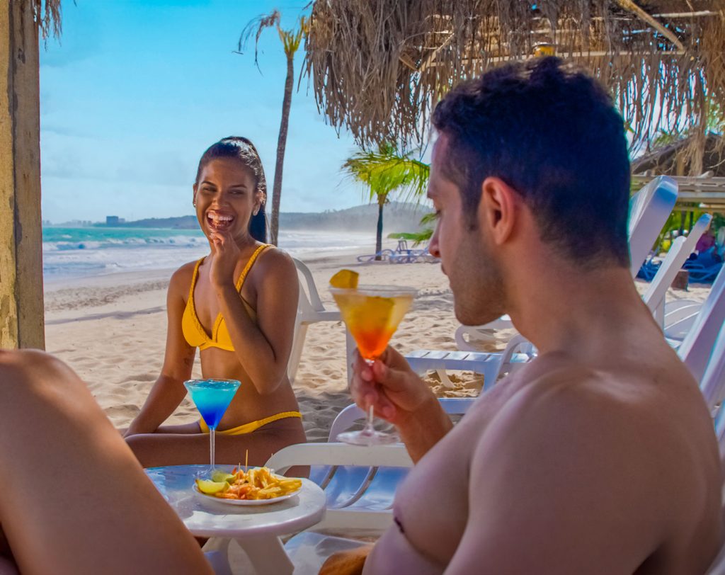 Casal na praia de Pratagy, sentados no espaço reservado aos hóspedes da categoria Premium Class.